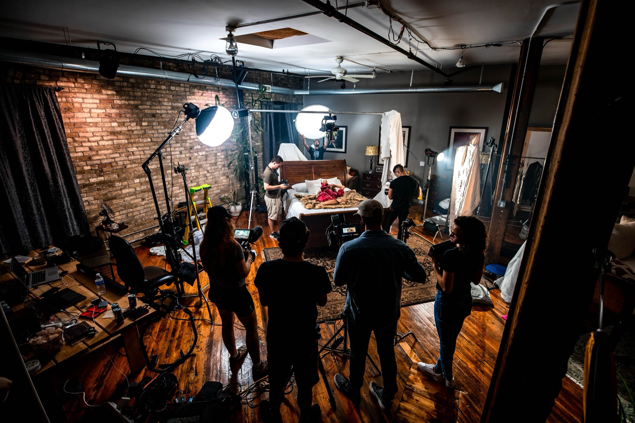 Crew filming a bedroom scene in an industrial loft studio.