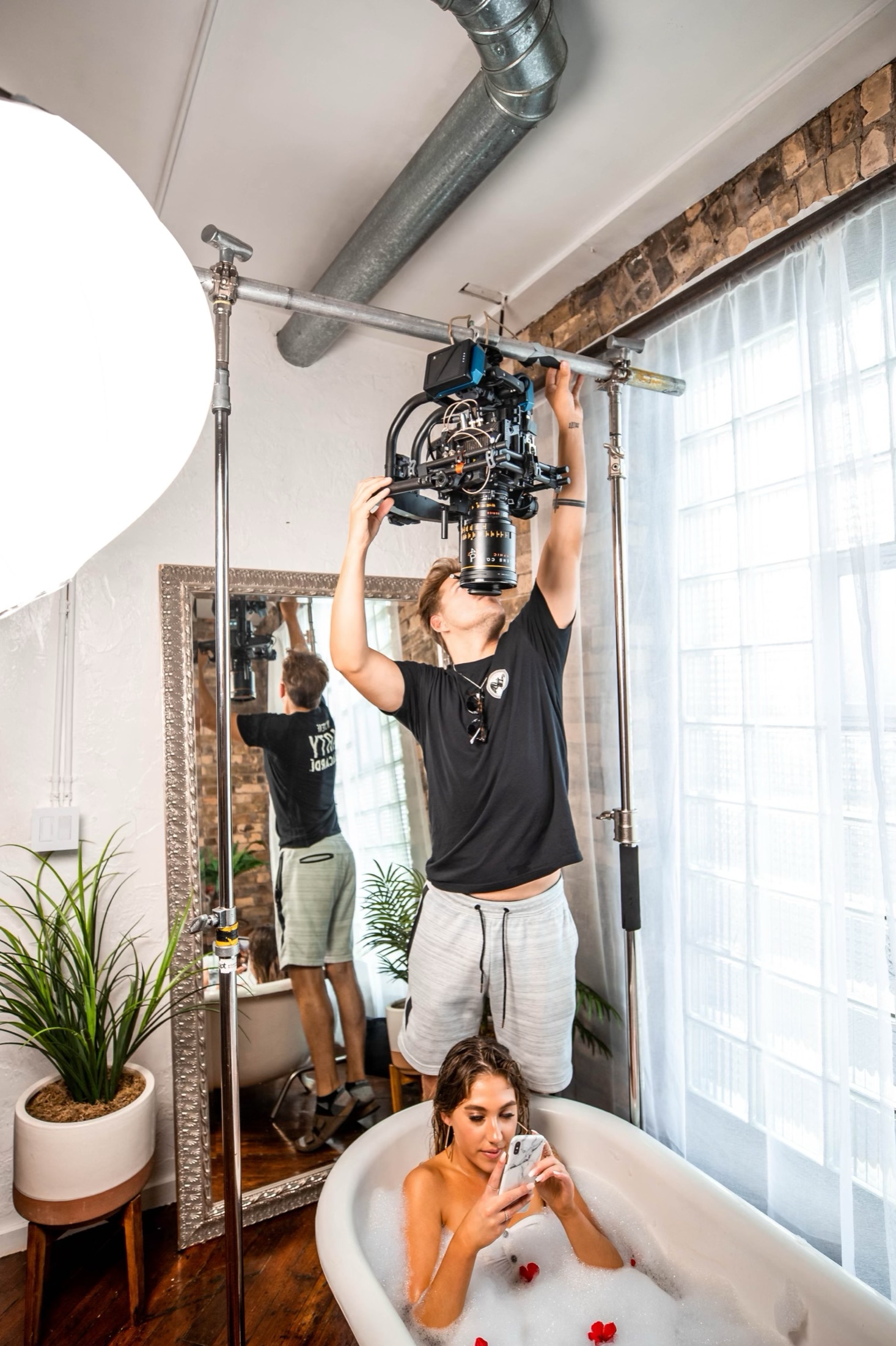 Overhead camera being adjusted above a bathtub scene on set.
