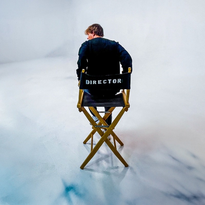 Joshua Moe seated in a director's chair on set.